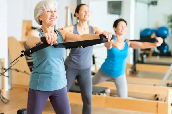 Toning Arms After 60: Empowering Womens Fitness Through Effective Weight Training 2 older woman doing weight training Sunbury-on-Thames and resistance in the gym to tone upper arms